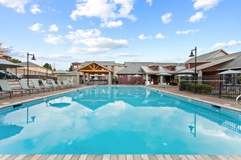 A large outdoor swimming pool with a wooden deck and lounge chairs.